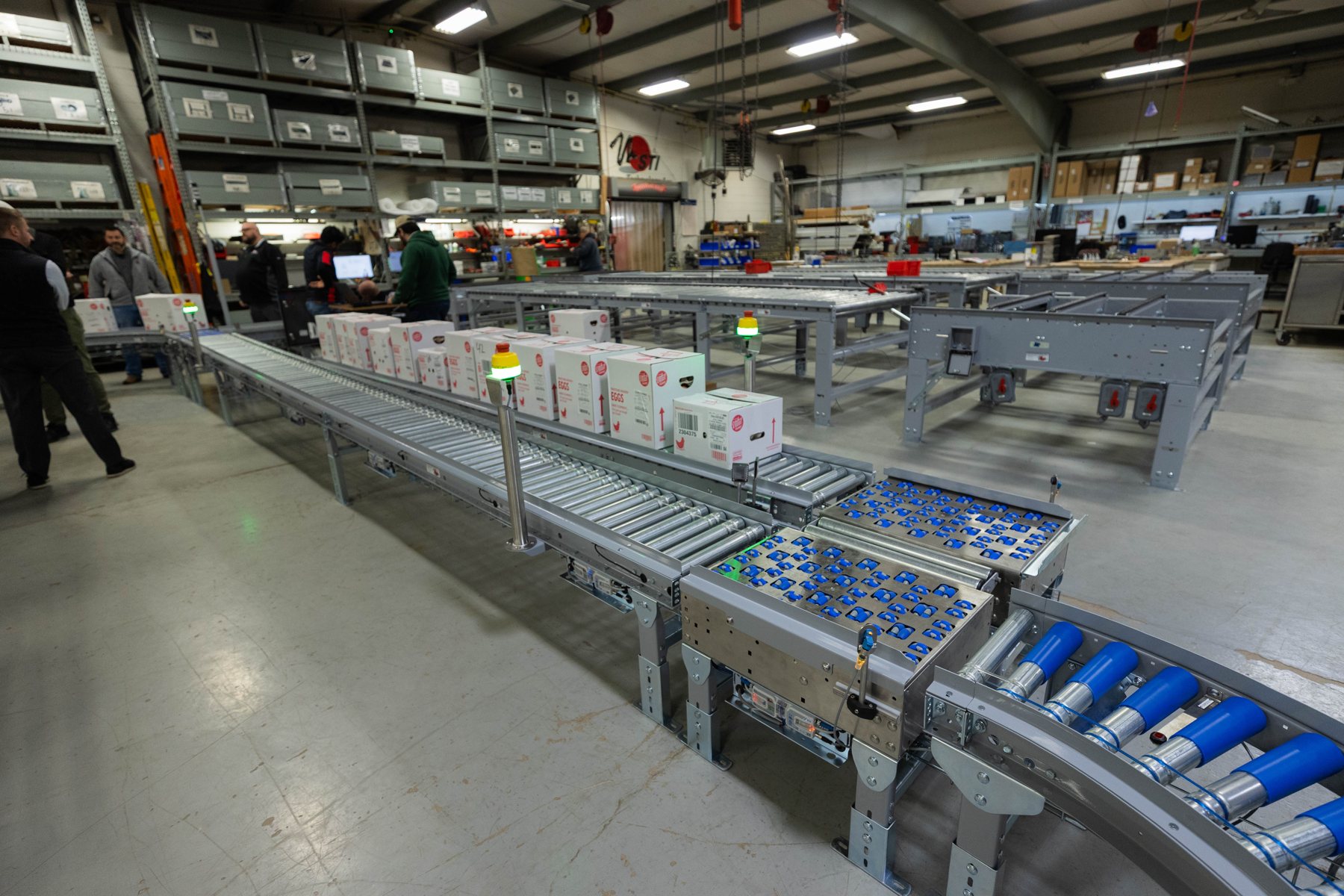 A System Technology conveyor line with powered roller sections and multi-directional transfers running cases in the Joliet shop